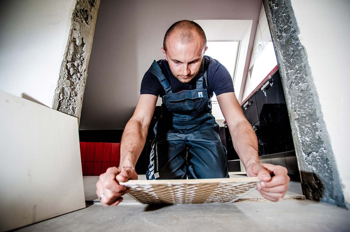 Handwerker legt Fliese auf Küchenboden