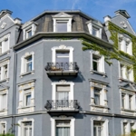 mietverwaltung-hausverwaltung-definition-aufgaben-arten-vertrag-kosten-ratgeber-tipps-mehrfamilienhaus-altbau-fassade-blau-balkon-fenster-himmel